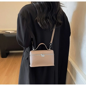 Close-up of a nude lychee leather crossbody bag with a heart-shaped metal zipper pull