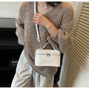 Detailed view of white textured leather handbag featuring unique dual heart-shaped metal zippers