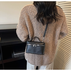 Detail of black lychee leather crossbody bag with silver heart-shaped zipper pulls