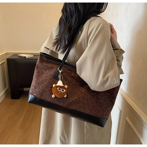 Detail of leopard print velvet tote bag with black leather straps and teddy charm