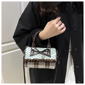 Detail of vintage cylinder bag with bow and heart charm on a model in black coat