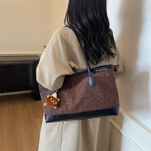 Large leopard print velvet tote bag with black leather straps and plush charm on model