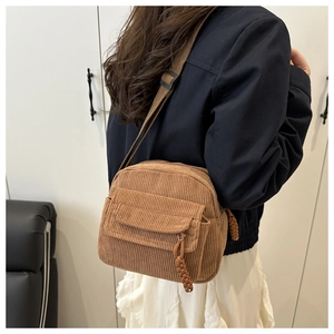 Detail of brown corduroy crossbody bag featuring a unique hand-woven zipper puller