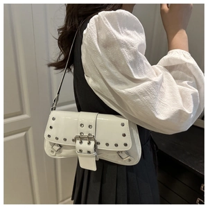 Close-up of white patent leather underarm bag with silver studs and buckle details