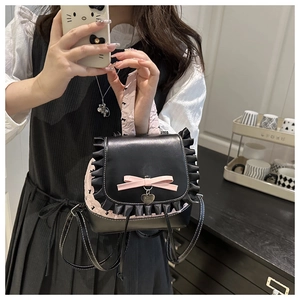 Detail of black glossy mini backpack with pink lace trim and heart metal pendant charm