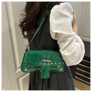 Macro view of green patent leather underarm bag with silver rivets and metal buckle detail