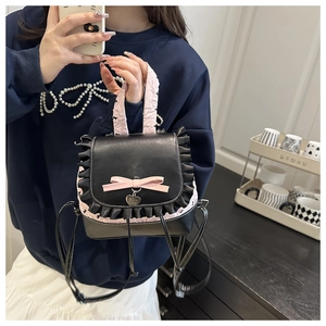 Detail of mini black and pink backpack with lace trim and heart pendant shown by model