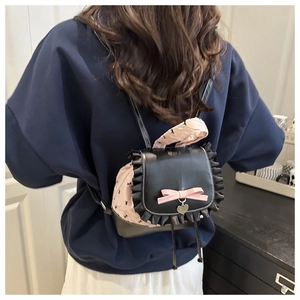 Detail of a chic mini backpack with black leather flap, ruffled edges and pink bow decoration