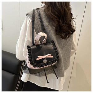 Side view of a girl wearing a black lace-trimmed mini backpack with pink floral embossing