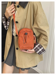 Detalle de bandolera naranja de tela oxford con cordón ajustable y bordado