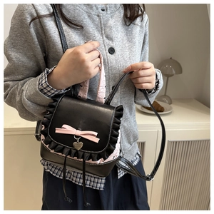Detail of black PU backpack featuring pink bow, lace trim and heart-shaped pendant