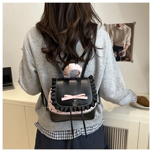Close-up of black leather mini backpack featuring pink silk bow and lace details