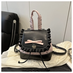 Close-up of heart charm and pink bow on black leather rucksack with ruffled edge