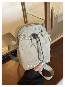 Detail of olive green nylon crossbody bag with drawstring design and woven rope accents