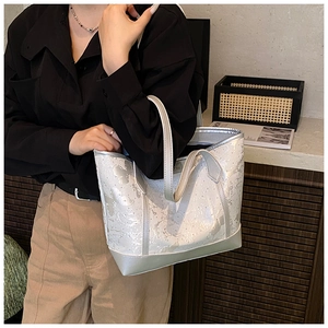 Detail of white tote bag with silver ink texture and glossy metallic reinforced trim