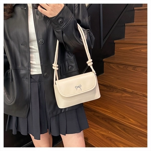 Détail du sac à épaule blanc crème avec nœud argenté et bandoulière à nœuds