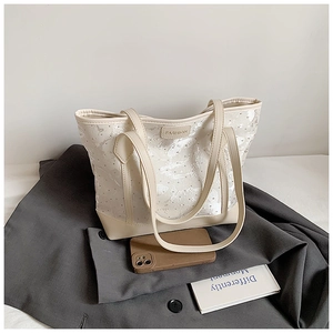 Detail of off-white tote bag with lace overlay and FASHION logo on a grey blazer