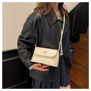 Détail d'un petit sac bandoulière blanc cassé en cuir avec boucle nœud argentée élégante