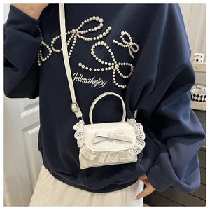 Detail of white PU leather crossbody bag featuring lace trim and a cute bow decoration