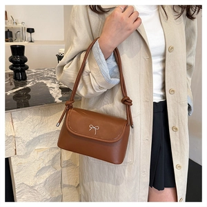 Détail du sac en cuir marron avec boucle nœud argentée et bandoulière à nœuds élégante