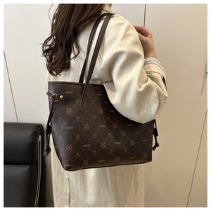 Détail du grand sac cabas en cuir marron avec motifs embossés porté à l'épaule