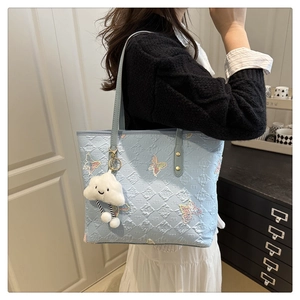 Détail du cabas bleu clair avec motifs papillons en relief et pendentif nuage doux