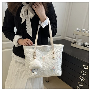 Gros plan du cabas blanc matelassé avec broderie papillon et pendentif nuage doux