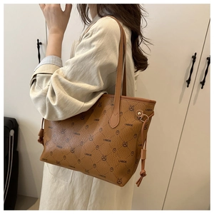 Close-up of brown pebbled leather tote with cartoon rabbit print and shoulder straps