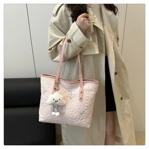Dettaglio della borsa tote rosa trapuntata con ricamo a farfalla e ciondolo a nuvola