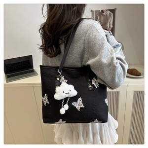 Détail du sac cabas noir avec broderie papillon colorée et breloque nuage sur le modèle