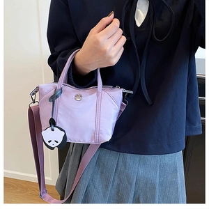 Detailed shot of purple nylon mini tote bag with crossbody strap and panda charm
