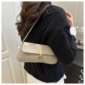 Detail of beige faux crocodile leather shoulder bag featuring a gold metal twist lock