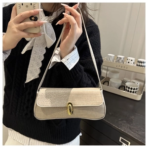 Detail of beige crocodile embossed leather underarm bag with gold oval twist lock