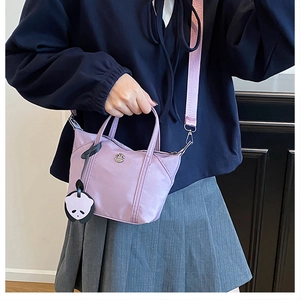 Detail of light purple nylon mini tote bag with panda charm and pink woven strap