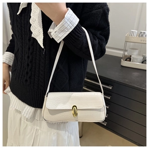 Close-up of white croc-embossed underarm bag featuring a golden metallic twist lock