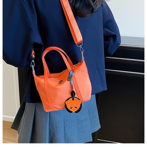 Close-up of vibrant orange nylon mini tote bag featuring a cute panda charm and metal logo