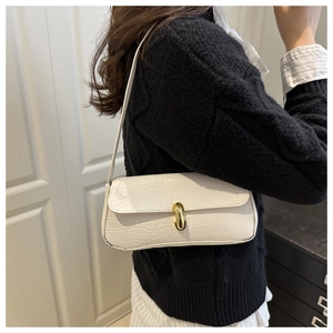 Detail of white crocodile pattern underarm bag featuring an oval gold metal buckle