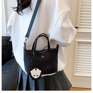 Detail of black nylon dumpling bag with adjustable wide strap and cute panda charm
