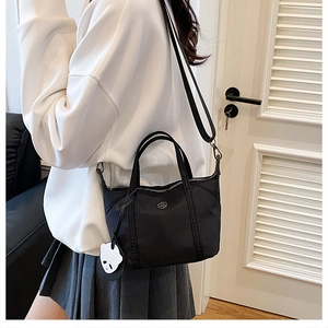 Close-up of black nylon mini tote bag with panda charm and adjustable shoulder strap