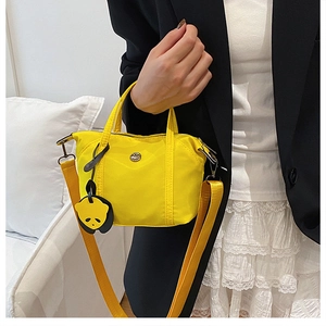 Detail of bright yellow nylon mini tote bag with cute panda charm and adjustable strap