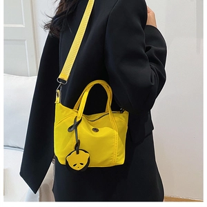 Detailed view of yellow crossbody bag with wide shoulder strap and panda charm accessory