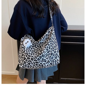 Dettaglio della borsa tote in tela leopardata con ciondolo a forma di orsetto bianco