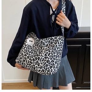 Dettaglio di una grande borsa tote leopardata con un portachiavi di peluche bianco laterale