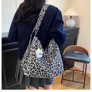 Détail du sac cabas imprimé léopard avec pompon blanc et large bandoulière à l'épaule