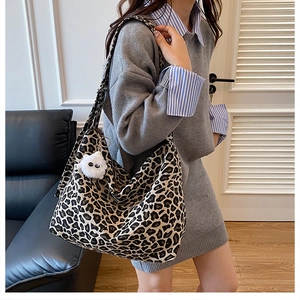 Vue détaillée du grand sac bandoulière en toile léopard avec un pompon blanc pelucheux