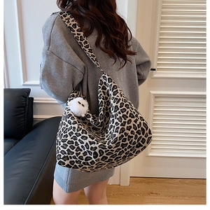 Détail d'un sac cabas léopard avec pendentif pompon blanc et bandoulière large