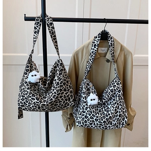 Détail de sacs bandoulière en toile léopard avec pendentifs en peluche sur un portant