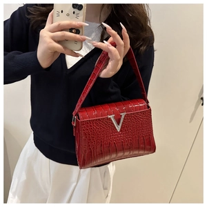 Detail of red croc-embossed leather handbag featuring a polished silver metal V-shaped buckle