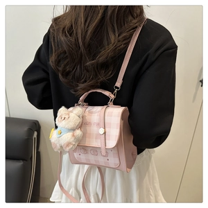 Detail of pink plaid handbag with cute bear print and white plush bear charm