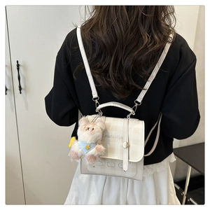 Detail of cream plaid mini backpack with bear charm and logo shown on model back